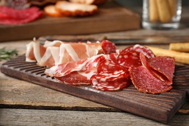 Photo of Cutting board with different meat delicacies on wooden table