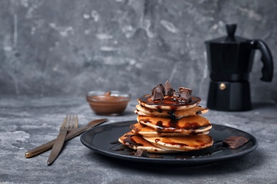 Tasty pancakes with chocolate on table