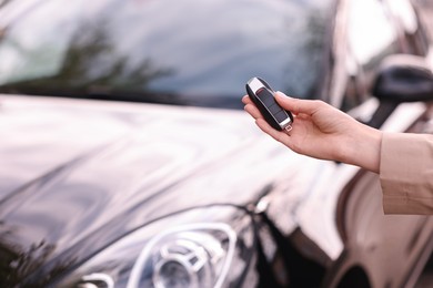 Photo of Woman holding car flip key near her vehicle outdoors, closeup