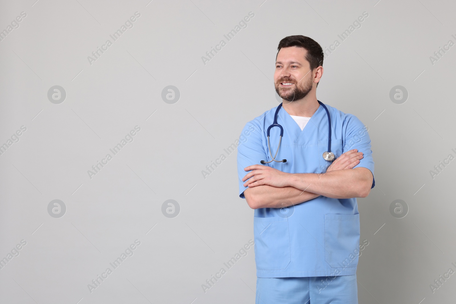 Photo of Portrait of smiling doctor on light grey background. Space for text
