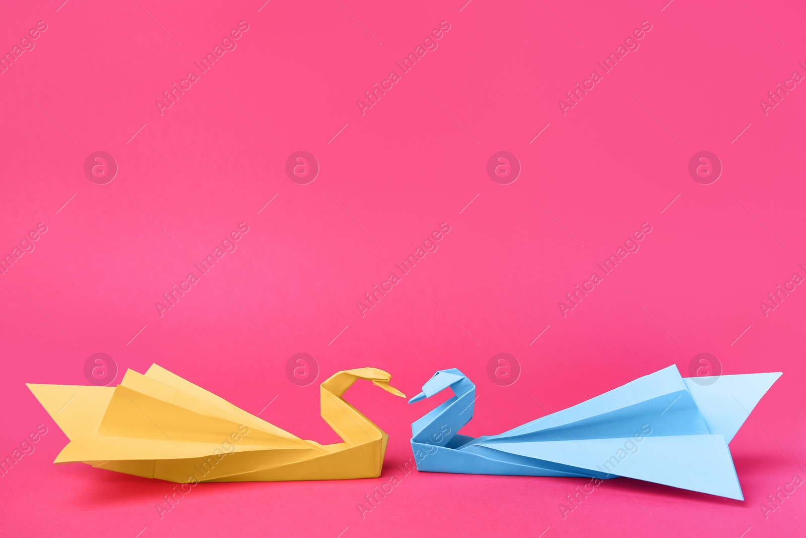 Photo of Paper swans on pink background, space for text. Origami art