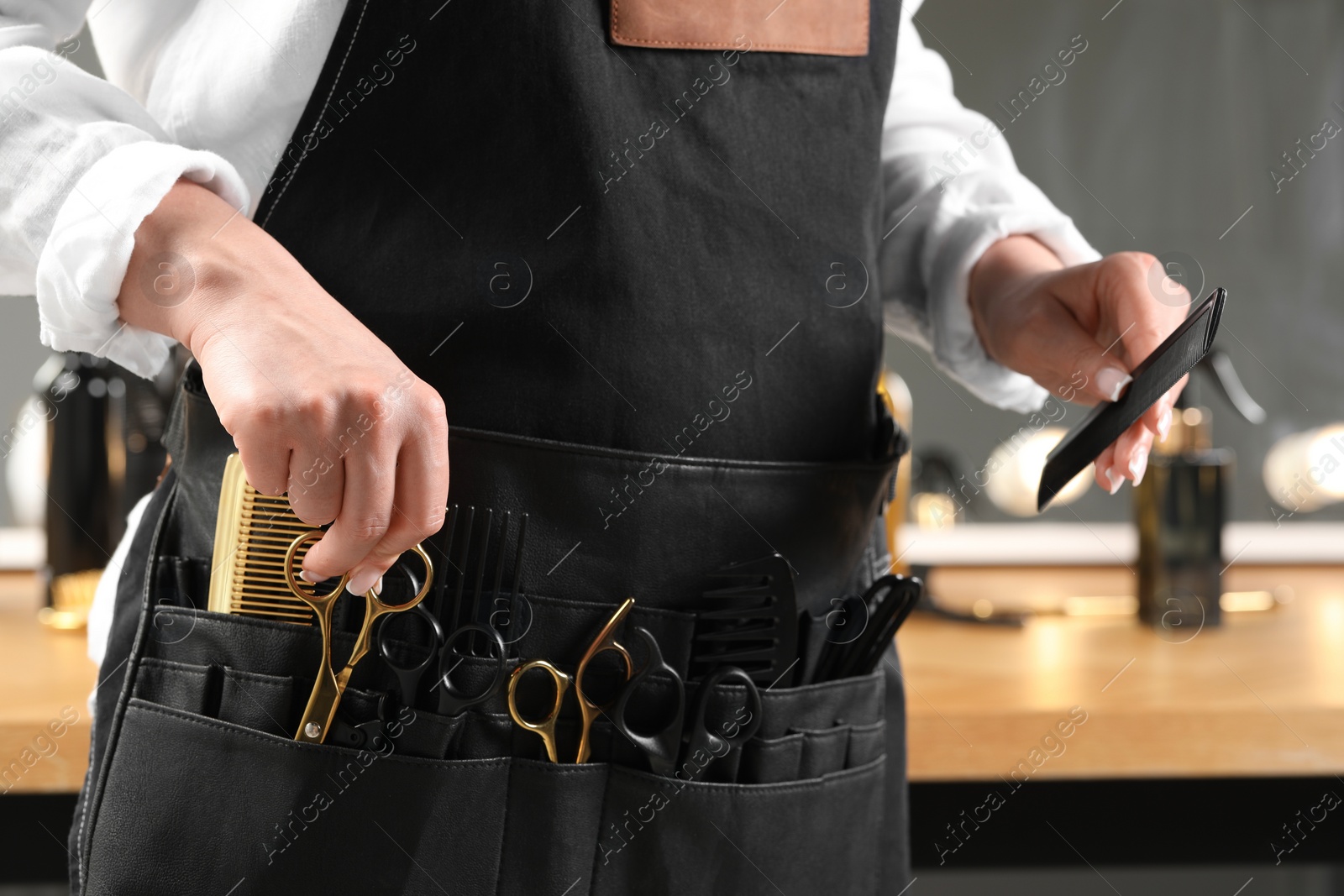 Photo of Hairstylist with professional tools in waist pouch in salon, closeup