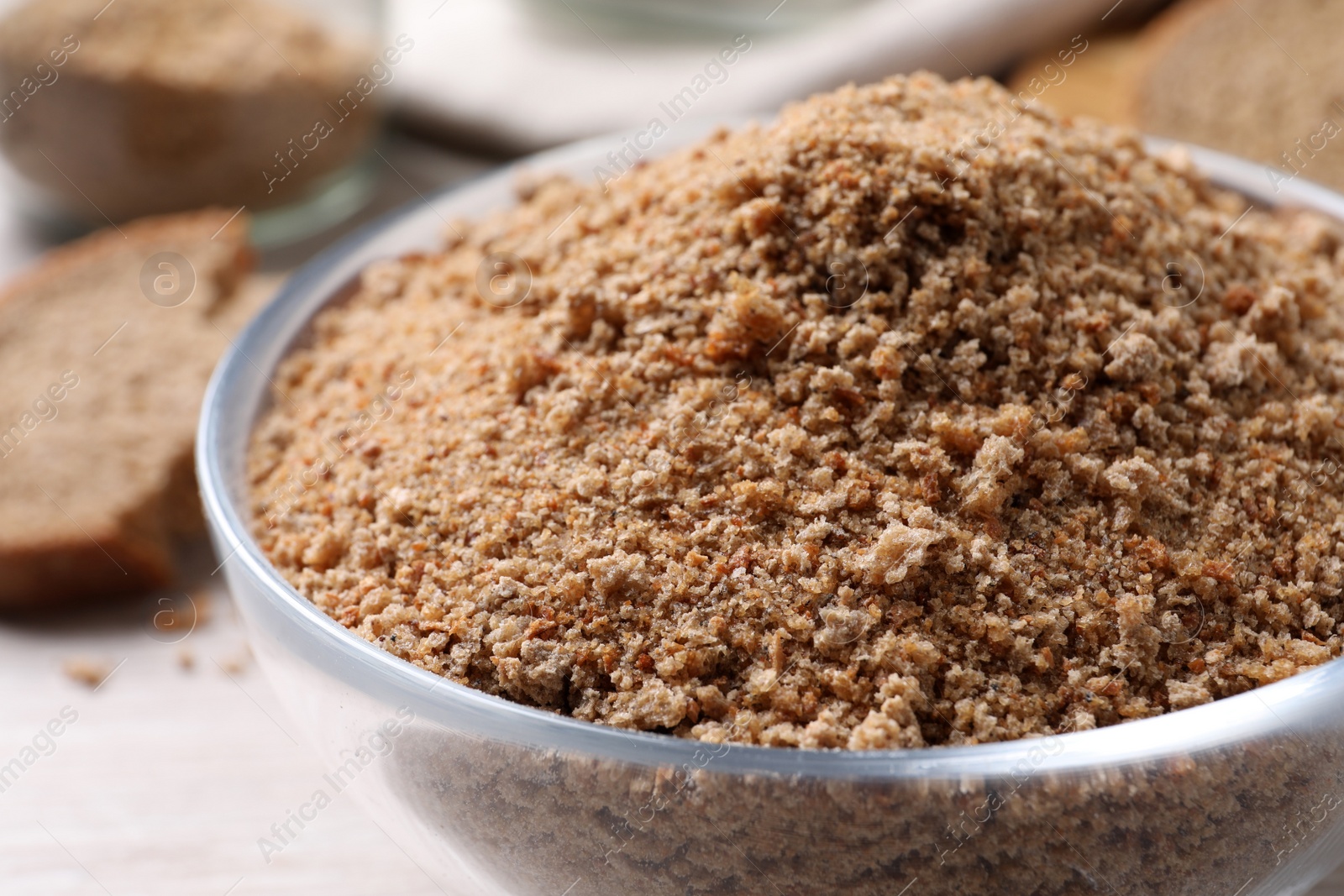 Photo of Fresh breadcrumbs in bowl on white wooden table, closeup