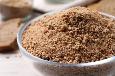 Photo of Fresh breadcrumbs in bowl on white wooden table, closeup