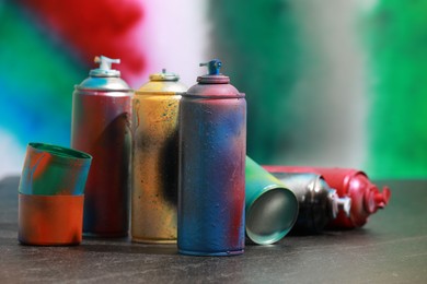 Photo of Many spray paint cans on gray surface against color background