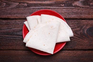 Photo of Delicious folded Armenian lavash on wooden table, top view