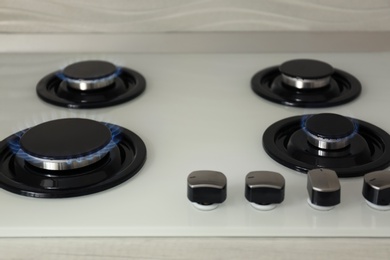 Photo of Gas burners with blue flame on modern stove