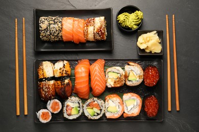 Photo of Delicious sushi rolls on black table, flat lay