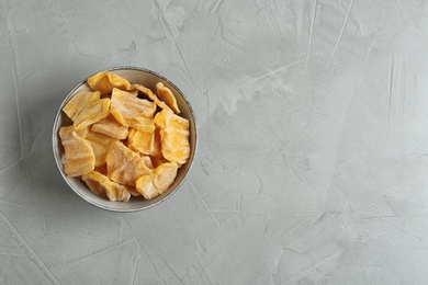 Delicious dried jackfruit slices in bowl on grey table, top view. Space for text