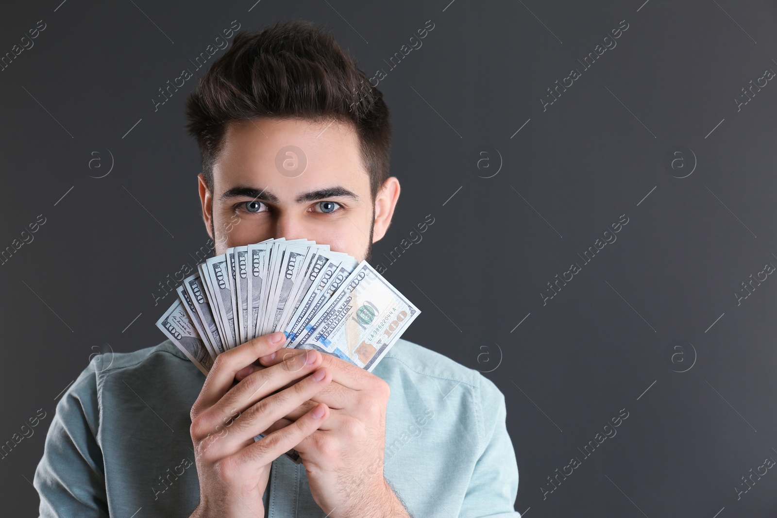 Photo of Happy young man with money on grey background. Space for text