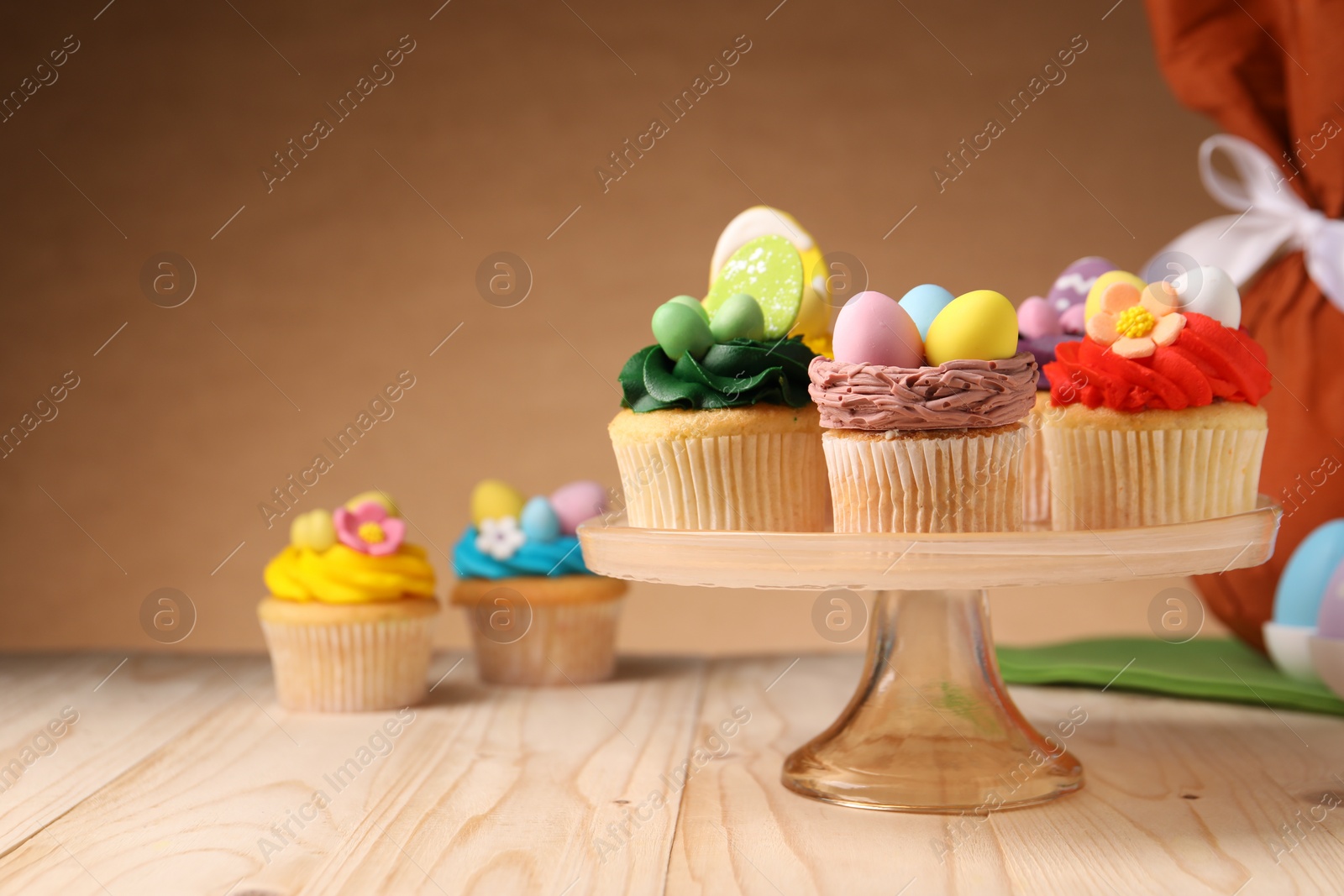 Photo of Tasty cupcakes with Easter decor on wooden table, space for text