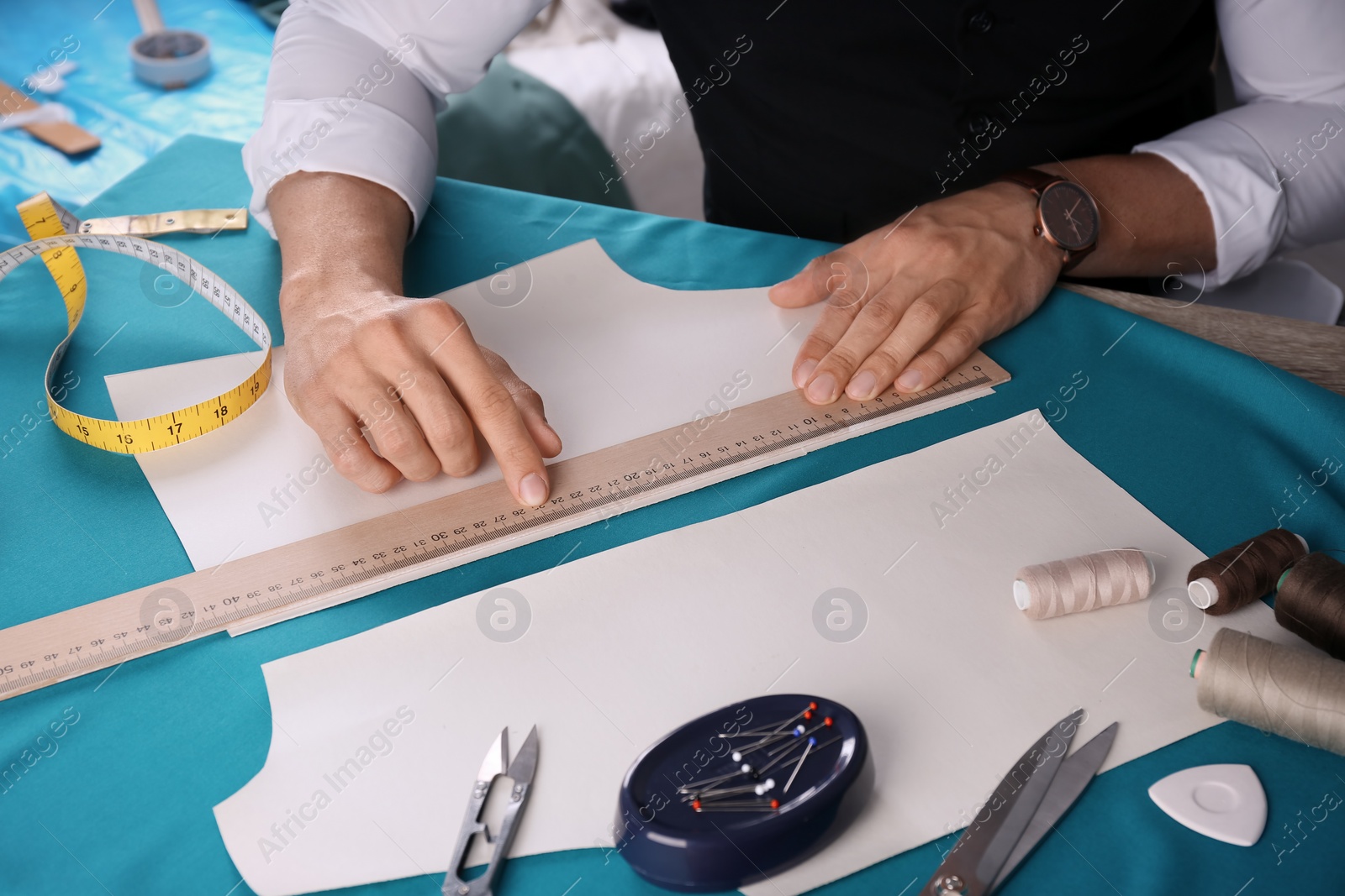 Photo of Tailor working at table in atelier, closeup