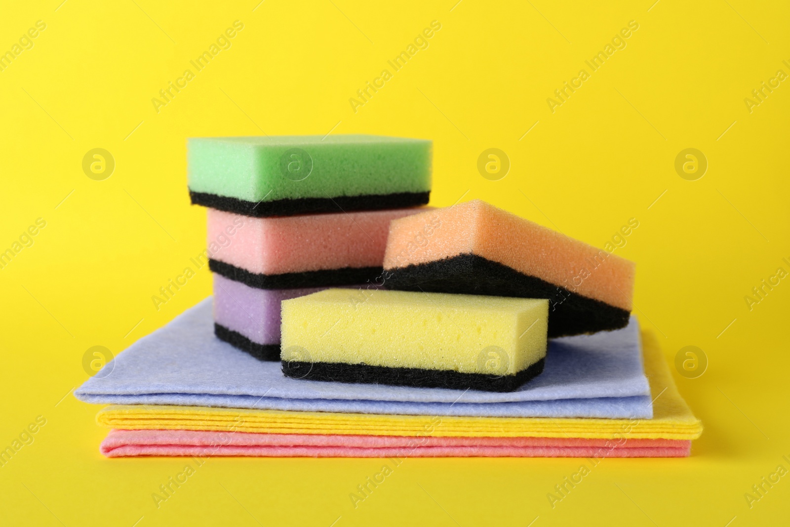 Photo of Cleaning sponges and rags on yellow background