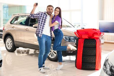 Photo of Happy couple with car key in modern auto dealership