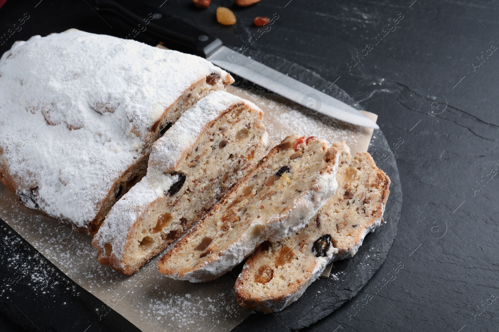 Photo of Traditional Christmas Stollen with icing sugar on black table