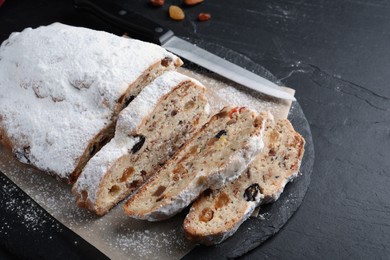 Photo of Traditional Christmas Stollen with icing sugar on black table