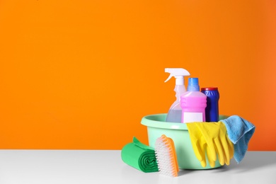 Bucket with cleaning supplies on color background