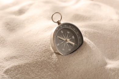 Photo of One compass on beach sand, closeup. Navigation equipment