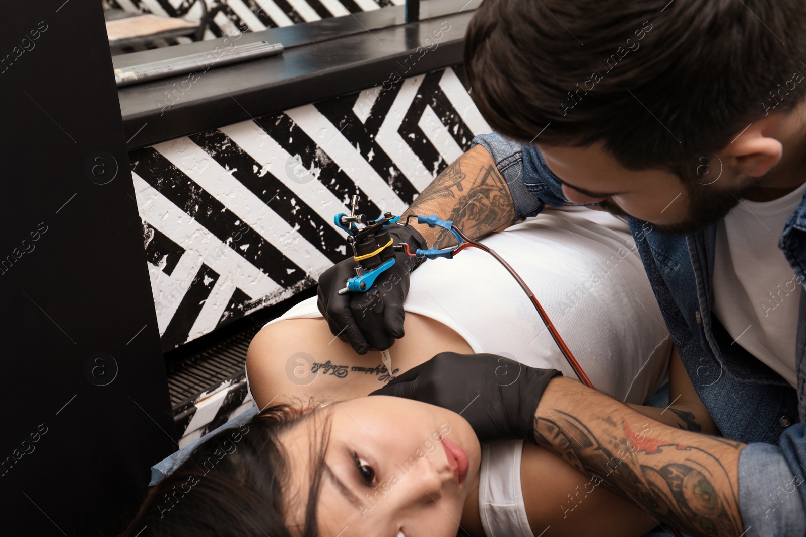 Photo of Professional artist making tattoo with machine in salon