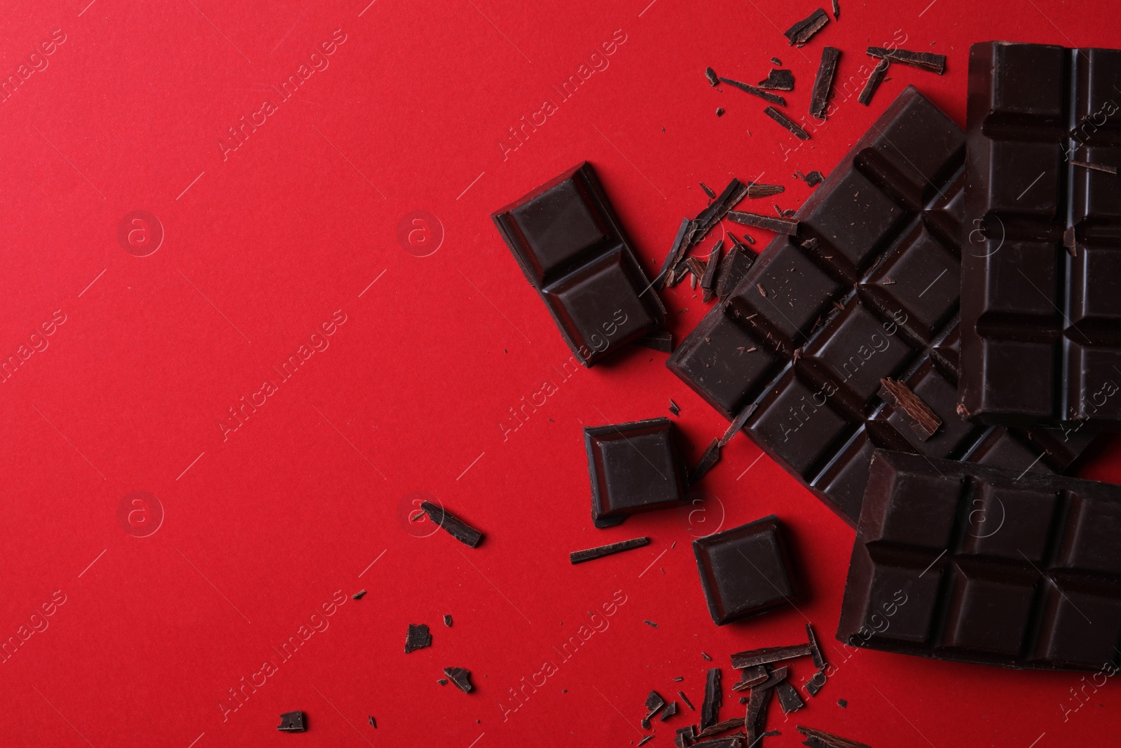 Photo of Tasty dark chocolate on red background, flat lay. Space for text