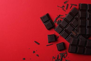 Photo of Tasty dark chocolate on red background, flat lay. Space for text