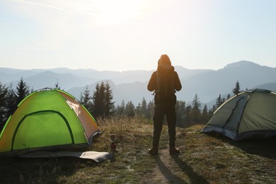 Photo of Tourist in mountain camping on sunny day, back view