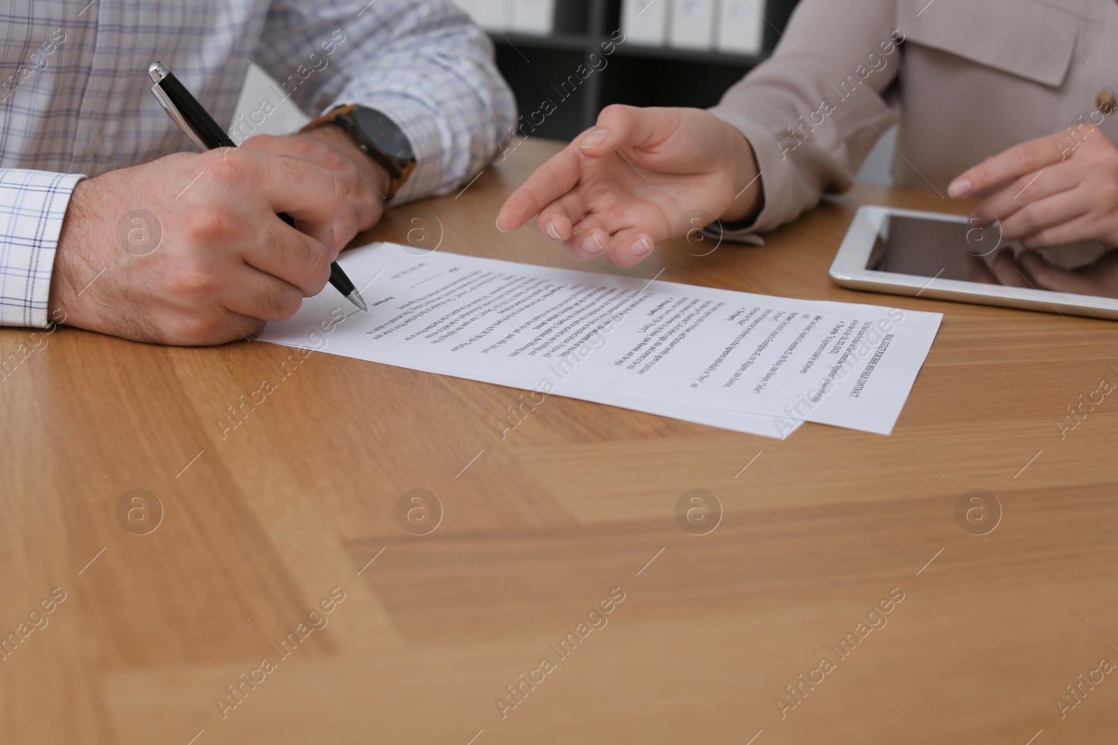 Photo of Businesspeople signing contract at wooden table, closeup of hands