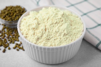 Photo of Mung bean flour in bowl and seeds on white table, closeup