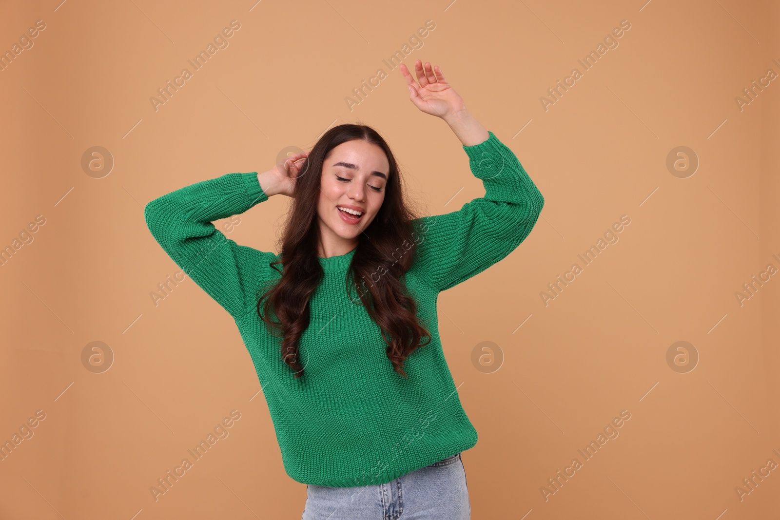 Photo of Beautiful young woman in stylish warm sweater on beige background