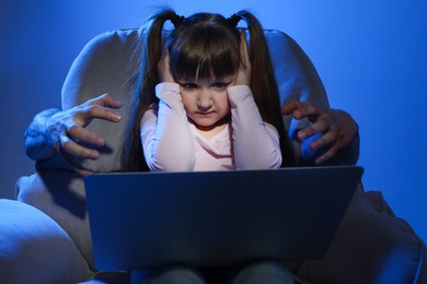 Photo of Stranger reaching frightened little child with laptop on color background. Cyber danger