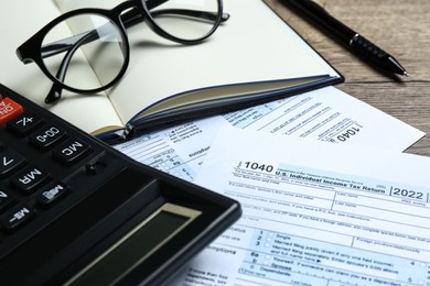 Photo of Calculator, pen, documents and glasses on wooden table, closeup. Tax accounting