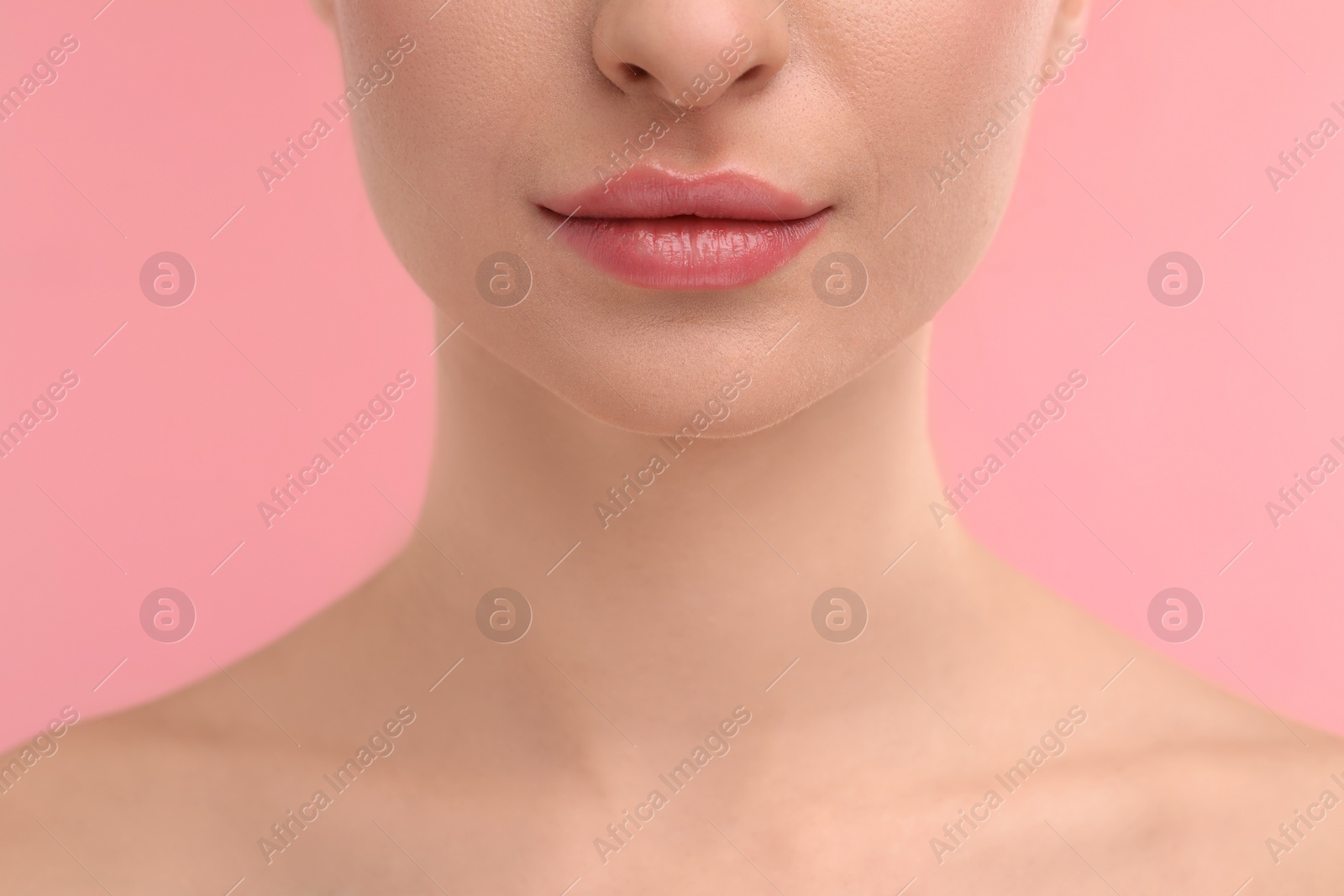 Photo of Young woman with beautiful full lips on pink background, closeup