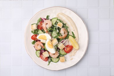 Photo of Delicious Caesar salad with shrimps on white tiled table, top view