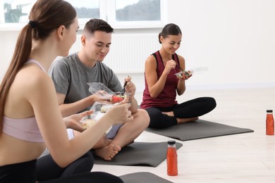 Photo of Group of people eating healthy food after yoga class indoors