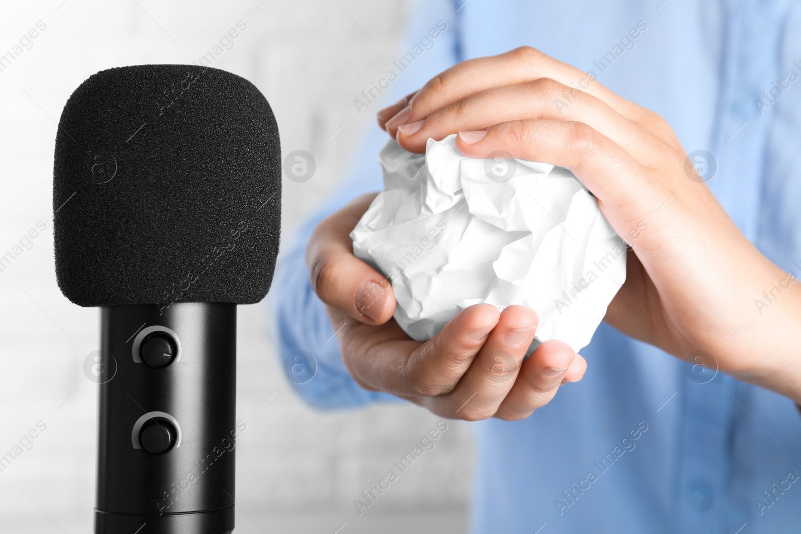 Photo of Woman making ASMR sounds with microphone and crumpled paper, closeup