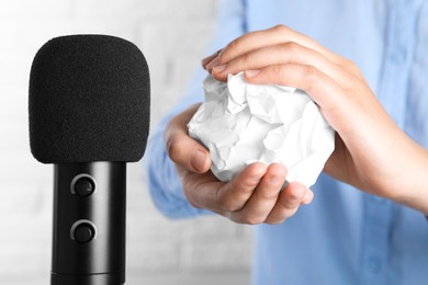 Photo of Woman making ASMR sounds with microphone and crumpled paper, closeup