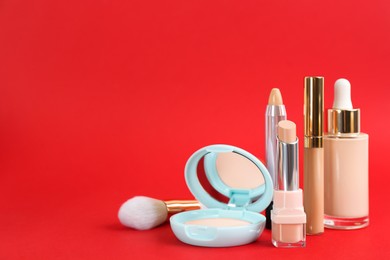 Photo of Foundation makeup products on red background, space for text. Decorative cosmetics