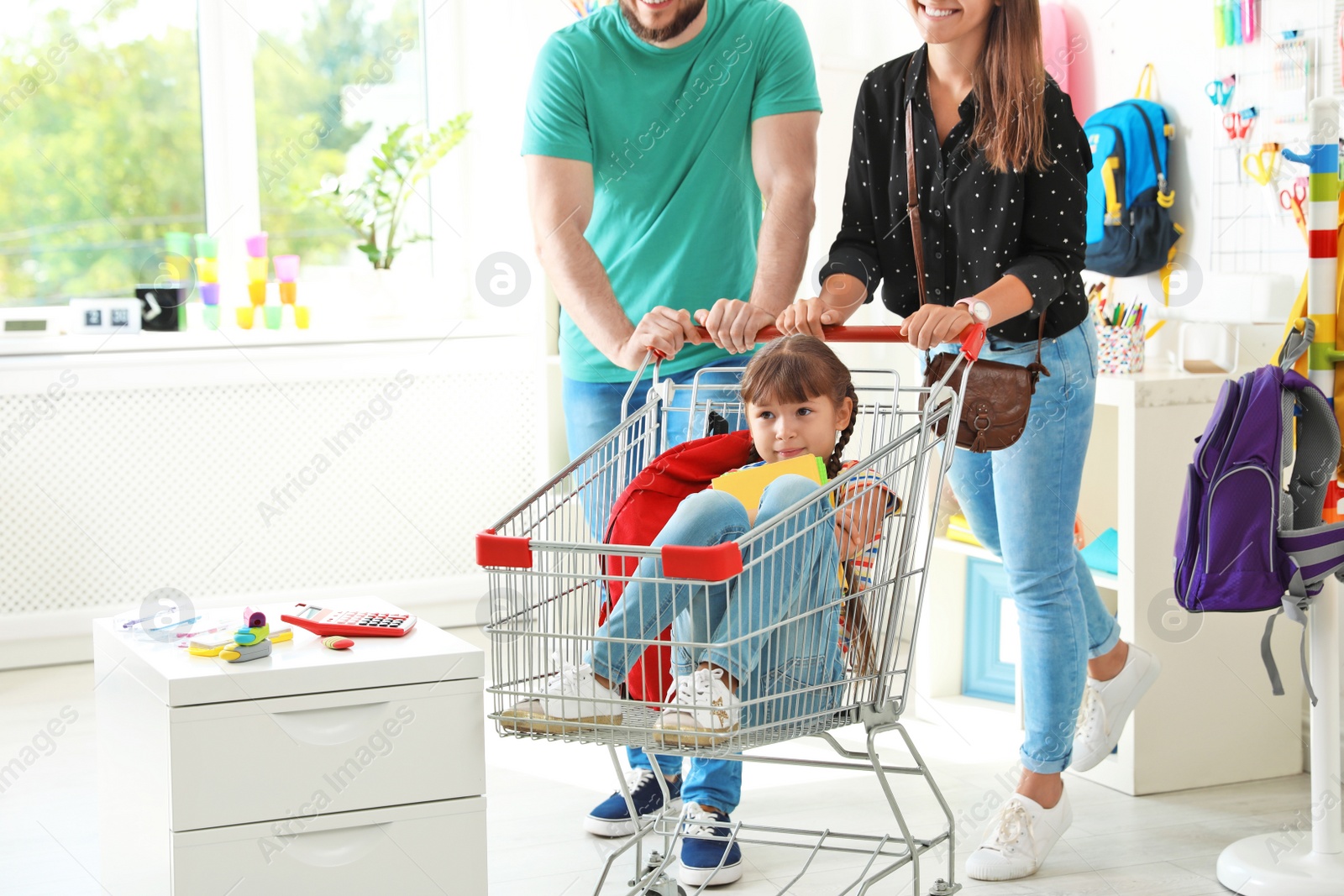 Photo of Parents riding their child in shopping trolley at school stationery store