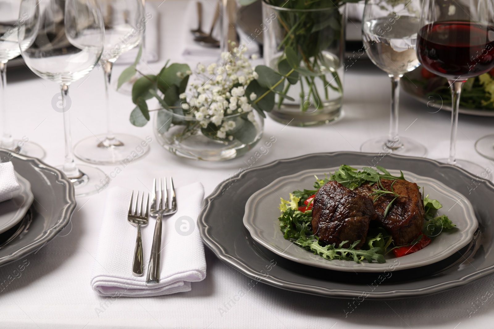 Photo of Delicious grilled meat with vegetables and wine served on table in restaurant