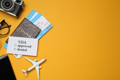 Flat lay composition with passport, toy plane and camera on orange background, space for text. Visa receiving