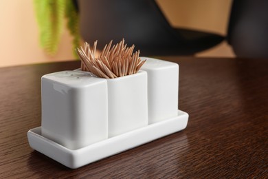 Photo of Holder with salt, pepper and toothpicks on wooden table. Space for text