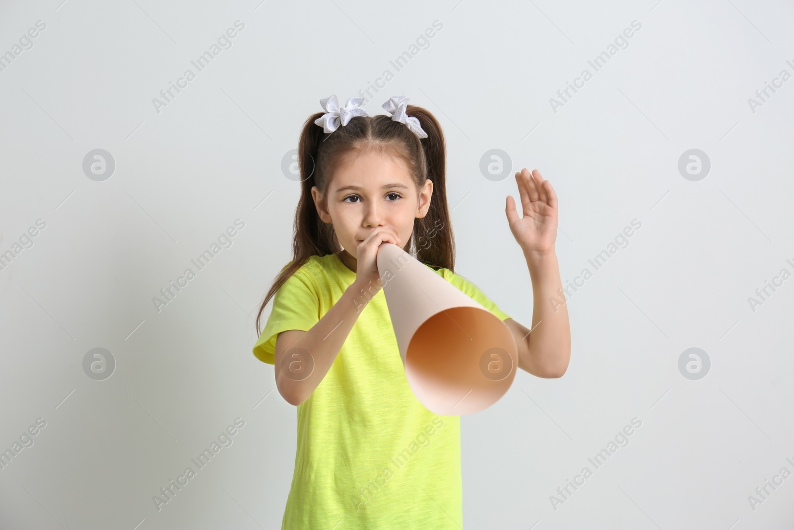 Photo of Cute little girl with paper megaphone on white background