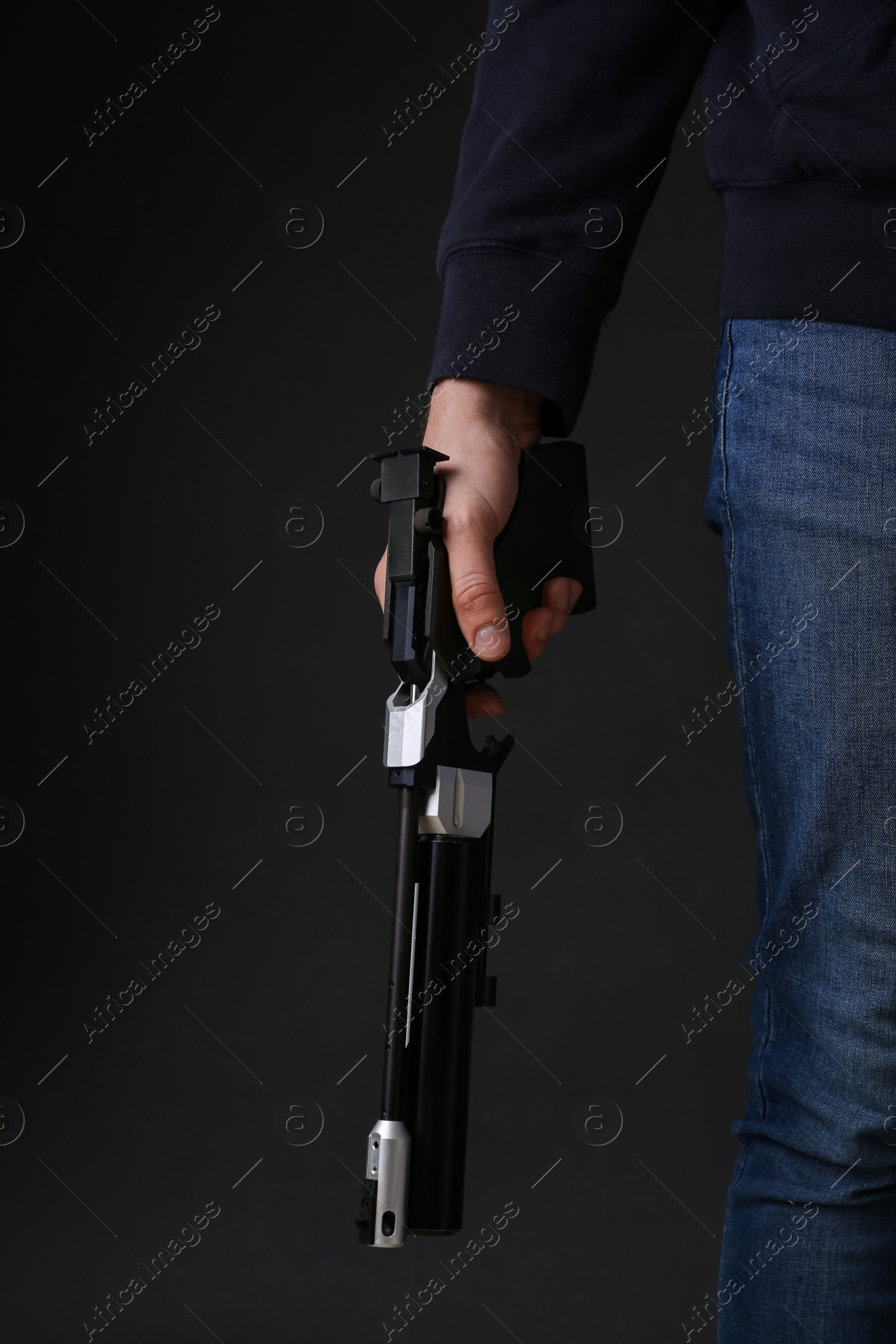 Photo of Gun shooting sport. Man holding standard pistol on dark background, closeup