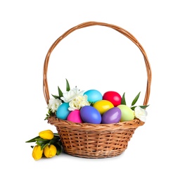 Photo of Wicker basket with bright painted Easter eggs and spring flowers on white background