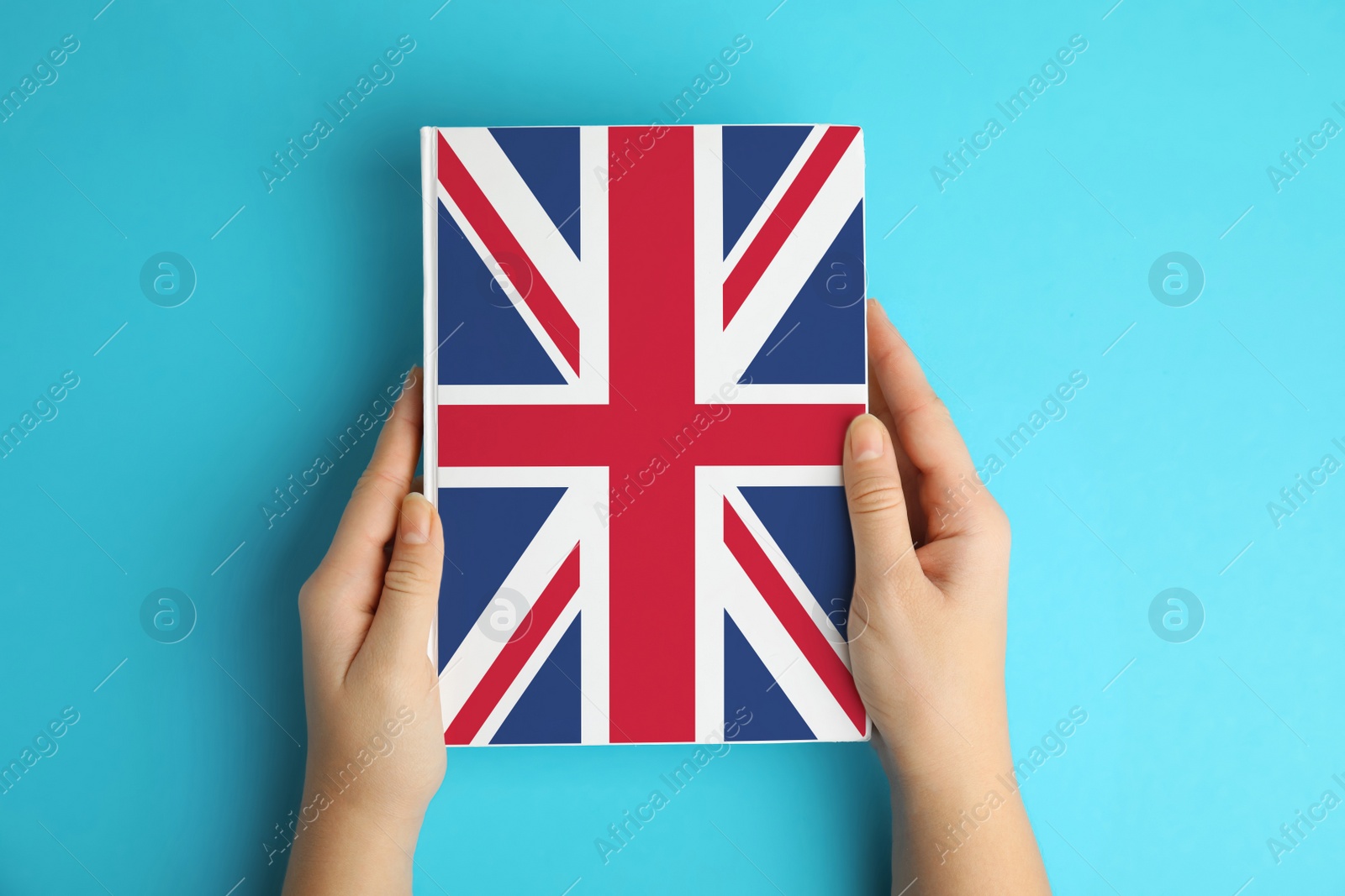 Image of Woman with book on light blue background, top view. Learning English