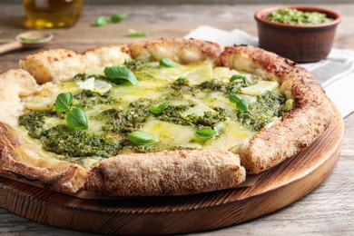 Photo of Delicious pizza with pesto, cheese and basil on wooden table, closeup