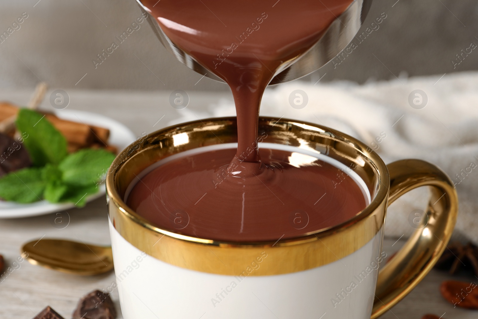 Photo of Pouring yummy hot chocolate into cup on table, closeup