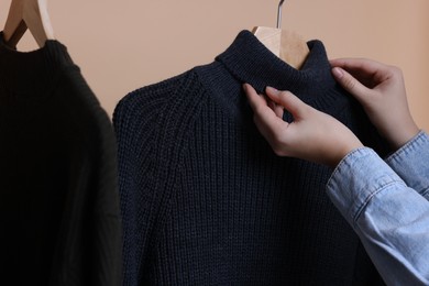 Photo of Woman taking casual sweater on beige background, closeup