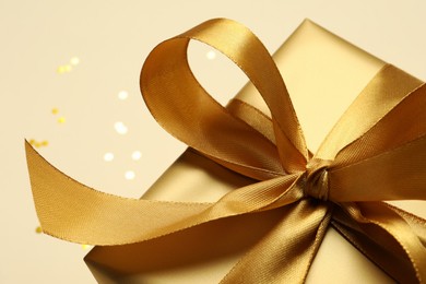 Photo of Beautiful golden gift box on beige background, closeup