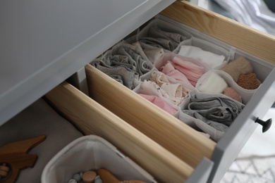 Photo of Open cabinet drawer with clothes in child room